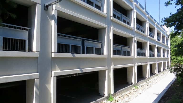 Side view of the parkade with a smooth precast concrete surface in view. It's a sunny day.