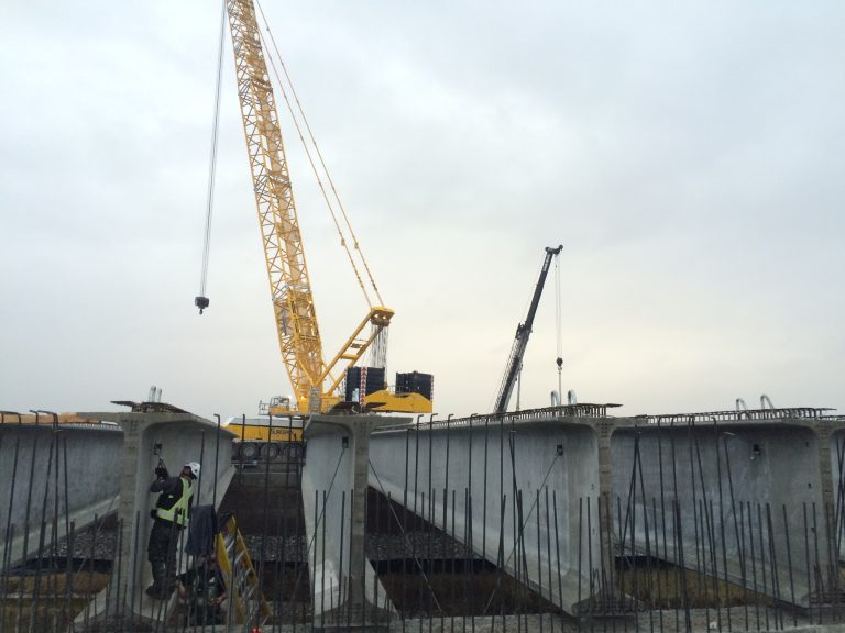 A ground level view of the girders in place. A crane can be seen in the background over a cloudy sky.